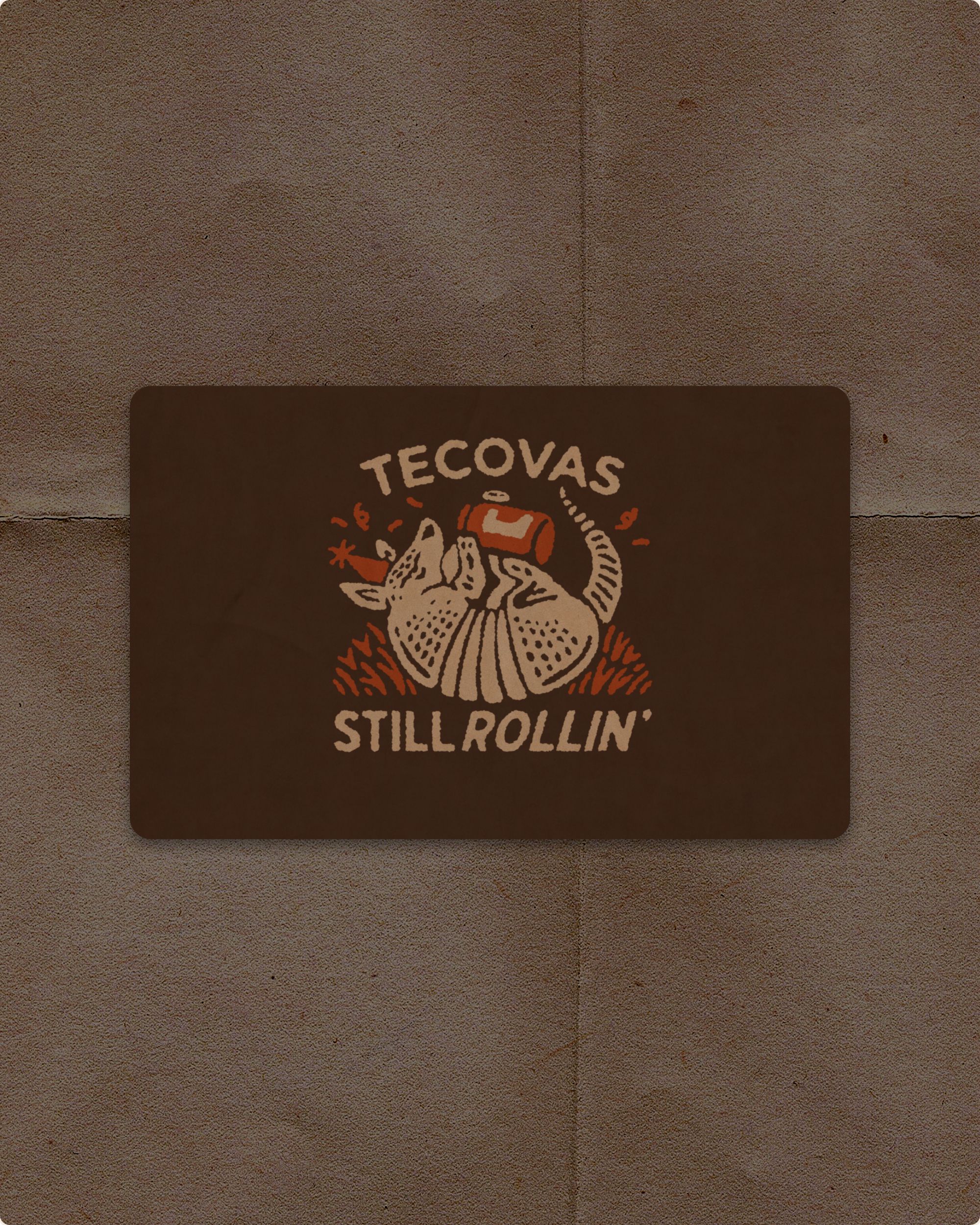 A sticker featuring an illustration of an armadillo wearing a party hat and holding a drink, with the text “TECOVAS STILL ROLLIN’”.