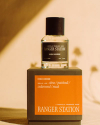 A bottle of Ranger Station 'High Horse' fragrance sits on a matching box. The label indicates scents of citrus, patchouli, cedarwood, and musk. The background features soft shadows.