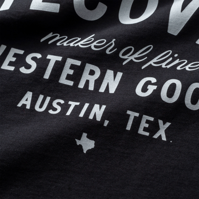 Close-up view of a black fabric with white text that includes "MAKER OF FINE WESTERN GOODS" and "AUSTIN, TEX." with a small Texas silhouette.