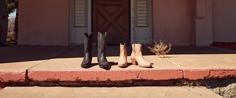 Exotic cowgirl boots lined up in front of a desert house