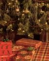 Wrapped presents with festive patterns and bows are placed under a decorated Christmas tree with ornaments, tinsel, and string lights.