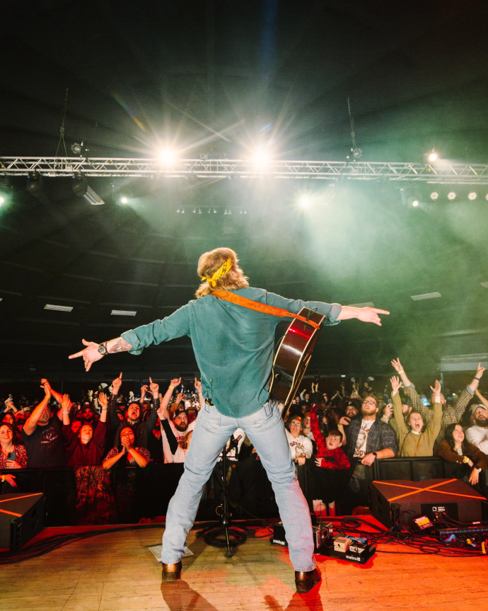 Charles Wesley Godwin performing with a guitar on stage.