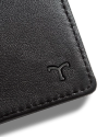 Close-up of a black leather wallet corner with an embossed "T" logo.