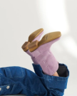 A person wearing denim pants and light purple heeled boots with tan soles is lying down with their legs raised.