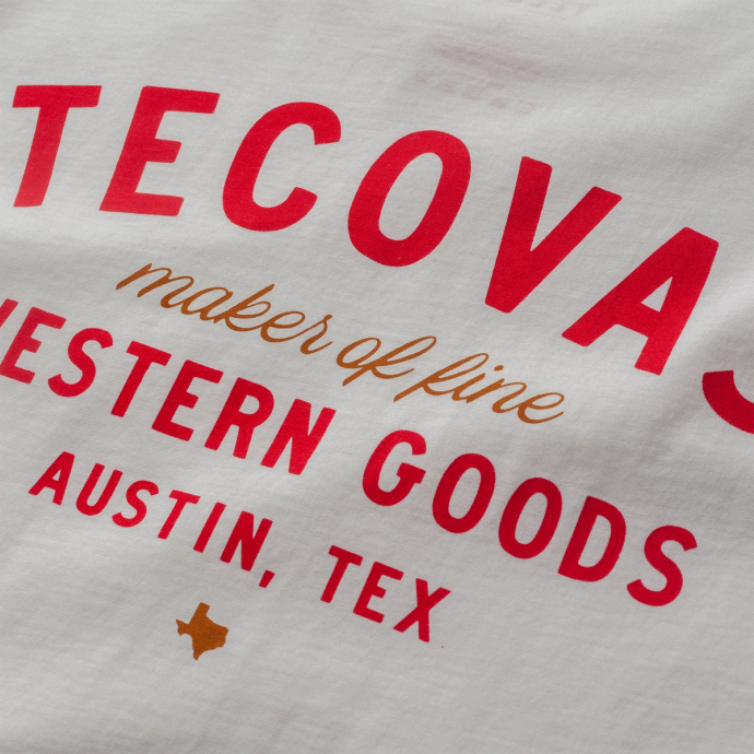 White T-shirt with red and gold text reading "TECOVAS maker of fine WESTERN GOODS AUSTIN, TEX". Small Texas silhouette in gold below.