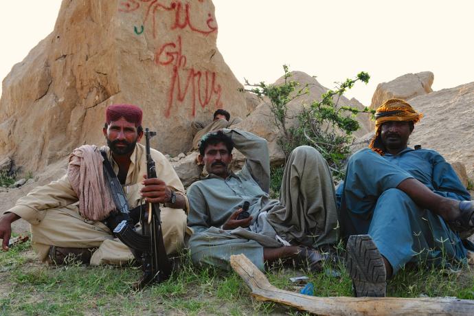 men sitting by a rock