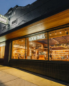 Storefront of a western-themed shop with a "GOOD TIMES" neon sign, displaying cowboy boots and western decor through large windows. The exterior has a black facade with illuminated signs and wood accents.