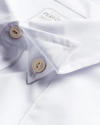 Close-up of a white dress shirt with a buttoned collar and visible buttons, displaying a neat and crisp fabric texture.