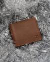 Brown leather wallet on shiny, silver, Christmas decor.