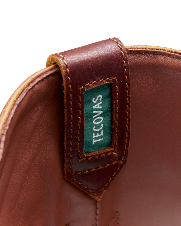 Close-up of a brown leather boot interior showcasing a green label with the text "Teconias" stitched on it.