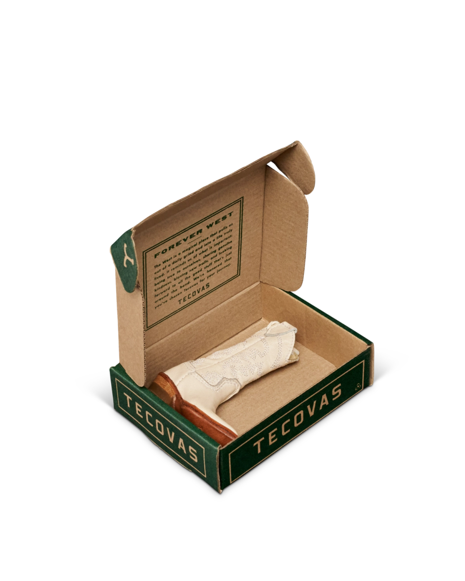 An open Tecovas box displays a single rolled-up white sock with a brown accent, alongside a printed message on the inside lid.