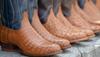 Four pairs of cowboy boots of different leathers in a line