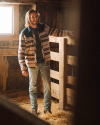 Man wearing Wildcat Overshirt with light wash denim jeans and cowboy boots in a stable.