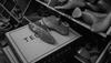 A pair of shoe lasts rest on a Tecovas box, surrounded by more shoe lasts on shelves in a workshop setting.