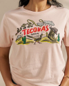 Woman wearing a pink Tecovas t shirt in a studio