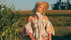 A woman in a floral dress standing in a corn field.