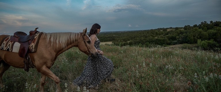 Woman wearing a dress leading a horse