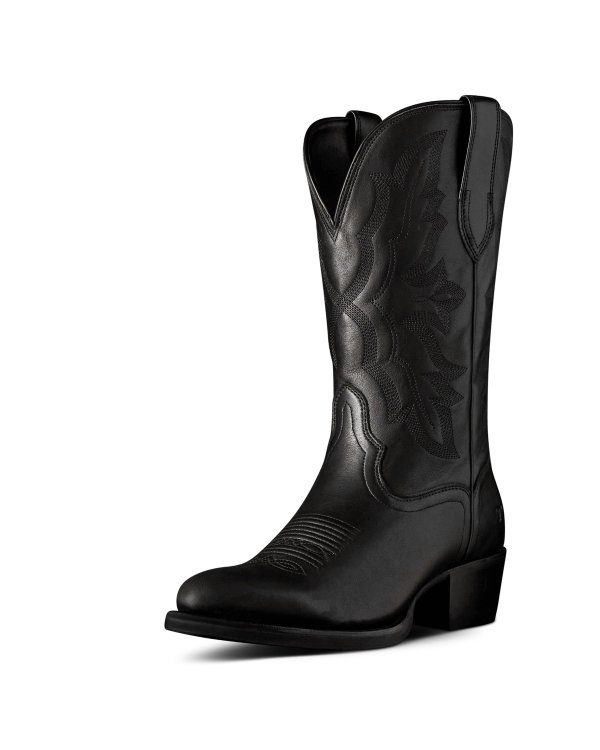 The Britt in Midnight Cowhide. Black leather cowboy boot crafted from Midnight Cowhide, featuring decorative stitching, a pointed toe, mid-calf height, pull tabs, and a low angled heel, displayed on a plain white background.