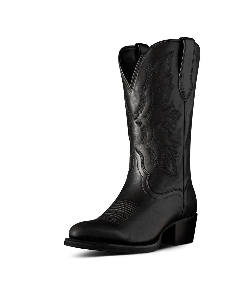The Britt in Midnight Cowhide. Black leather cowboy boot crafted from Midnight Cowhide, featuring decorative stitching, a pointed toe, mid-calf height, pull tabs, and a low angled heel, displayed on a plain white background.
