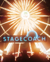 Brightly lit Ferris wheel glowing against a night sky with a neon sign below reading "Stagecoach" in front of silhouetted crowd.