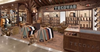Tecovas store display with shelves of cowboy boots, racks of folded shirts, wooden decor, and a counter, set in a well-lit retail environment.