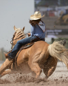 Person in a cowboy hat riding a horse, turning swiftly on a dirt arena during a rodeo event.