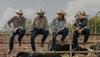 4 men on a corral fence 