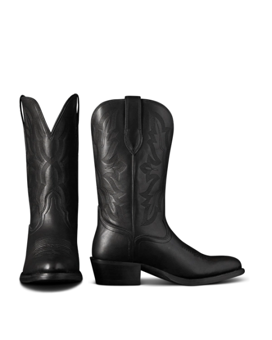 The Britt in Midnight Cowhide. Two black leather cowboy boots crafted from midnight cowhide with decorative stitching are shown; one boot faces forward, while the other is viewed from the side.