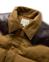 Close-up of a brown and tan jacket featuring a collar and two dark brown shoulder patches. The label reads "Tecoma of Austin, Texas.