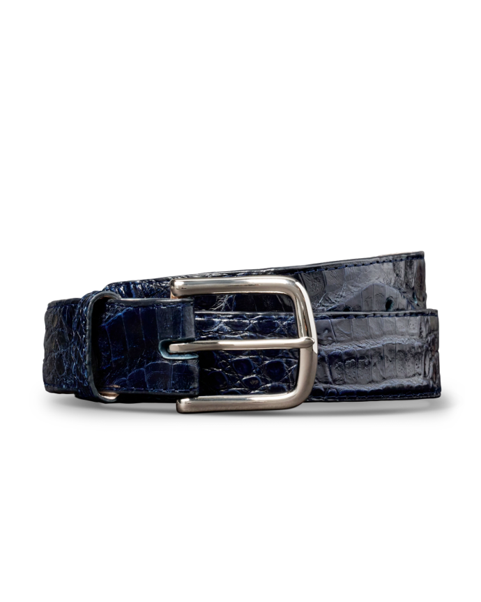 A rolled-up dark blue crocodile-patterned leather belt with a shiny silver buckle against a black background.