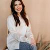 A woman in jeans and a white shirt sitting on a wooden chair.