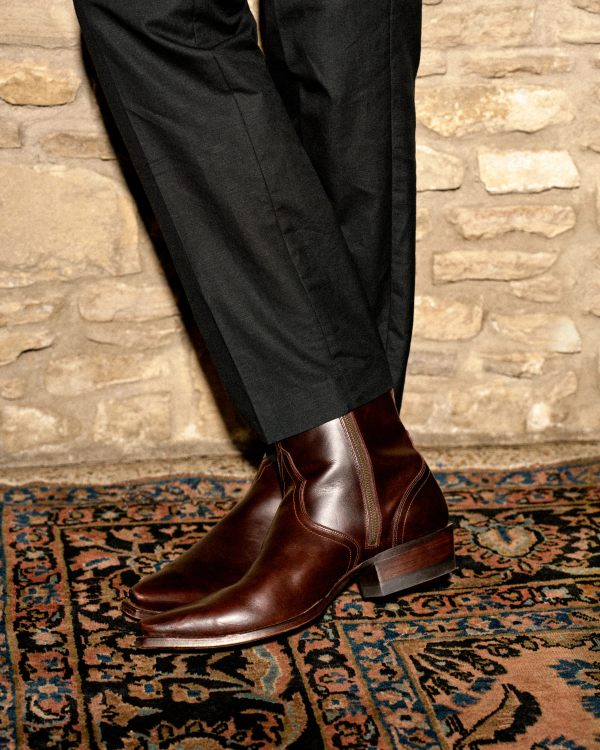 The Blaze in Dark Copper Cowhide. Dark copper cowhide zip-up ankle boots worn with black trousers.