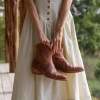 Woman in white dress holding pair of booties