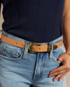 Closeup of woman wearing the art deco belt in tan with denim shorts in a studio