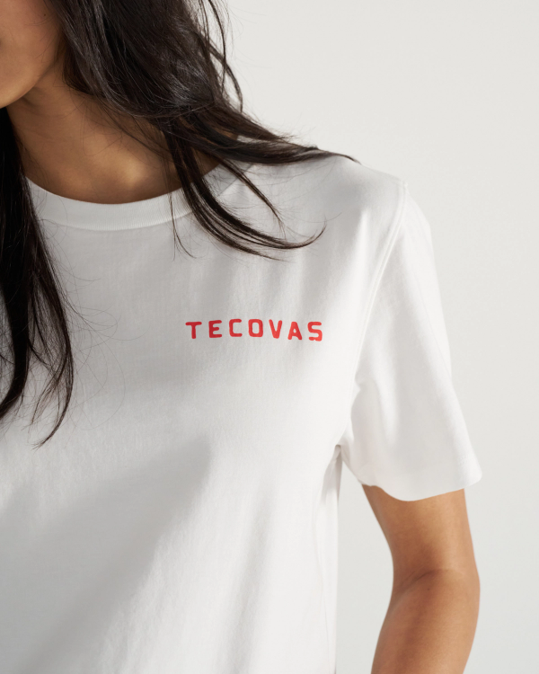 Close-up of a person wearing a white t-shirt with the word "Tecovas" printed in red on the chest. The person's face is partially out of frame.