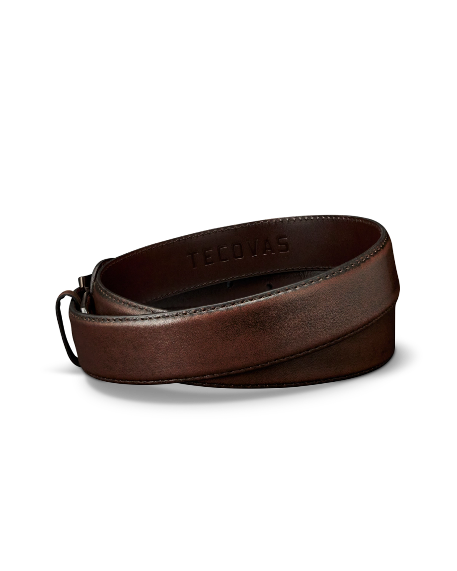 A rolled-up brown leather belt with the word "TECOVAS" embossed on the inside, displayed on a plain white background.