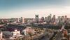 Aerial view of Nashville skyline at sunset featuring prominent buildings and nissan stadium, with soft pink hues illuminating the cityscape.