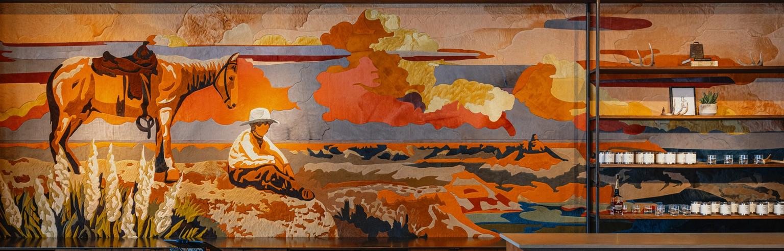 A mural depicting a man sitting on the ground next to a saddled horse, with a colorful sky and landscape in the background.