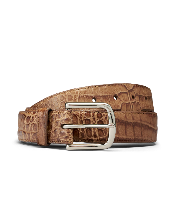 Brown leather belt with a crocodile pattern and a silver rectangular buckle, coiled on a plain white background.