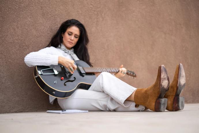 woman songwriting and sitting by a wall