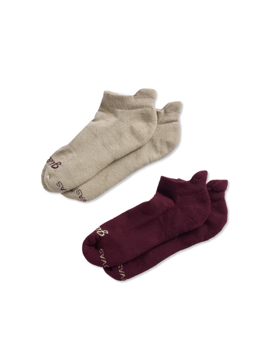 Two pairs of ankle socks, one beige and one dark red, are displayed on a black background.