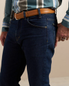 A person wearing dark blue jeans, a brown leather belt, and a blue striped shirt stands with a hand resting in their pocket.