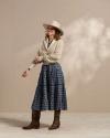 Woman wearing a blue dress, sweater, and brown cowgirl boots in a photo studio