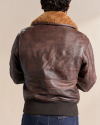 A person with short, dark hair is shown from the back, wearing a brown leather jacket with a fur collar and blue jeans.