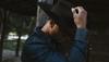 Man wearing umber cowboy hat and denim shirt looking down