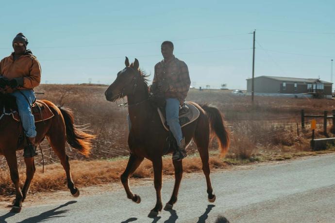 two men on horses on a road