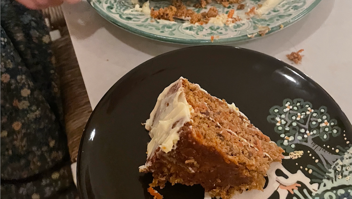 Half of a carrot cake on one plate and a slice of it on another.