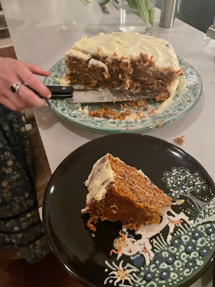 Half of a carrot cake on one plate and a slice of it on another.