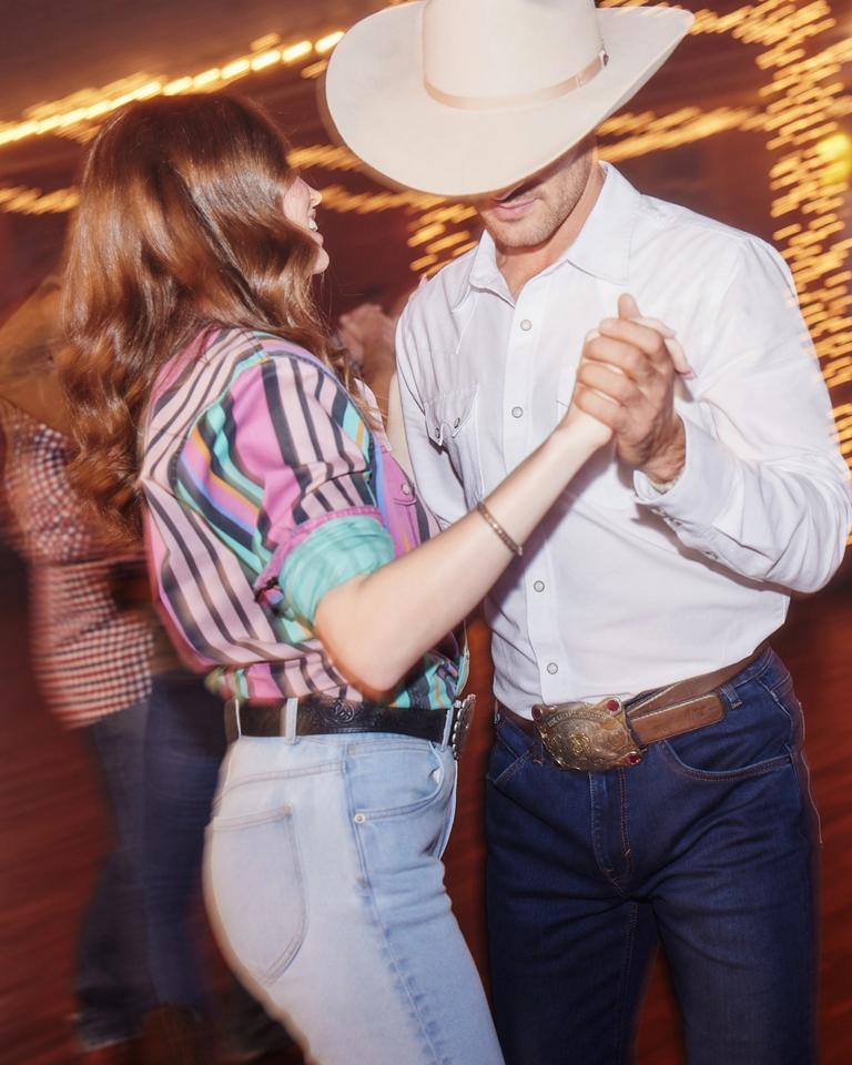 A couple in cowboy hats dancing at a party.