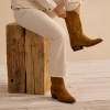 Woman in white denim pants putting on suede cowgirl boots
